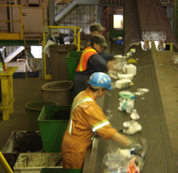 Waste sight employees sorting recyclables on convertor belt.